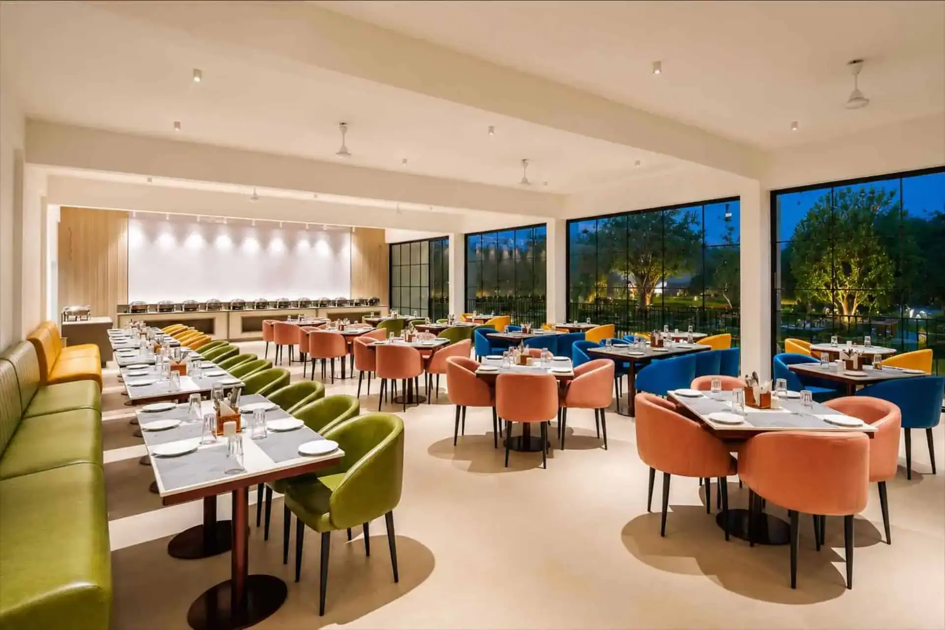 Vega Munnar Resort restaurant with colourful velvet chairs and buffet counter at night