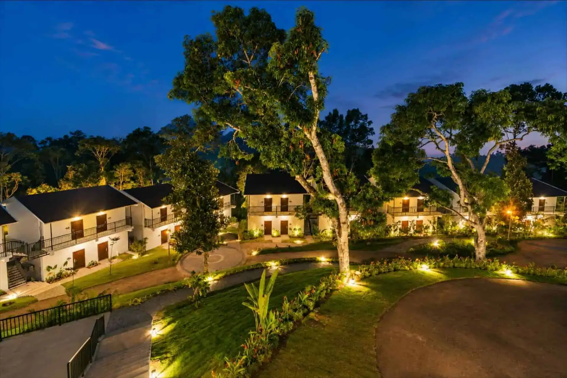 Night compound with dramatically uplighted mango trees in courtyard