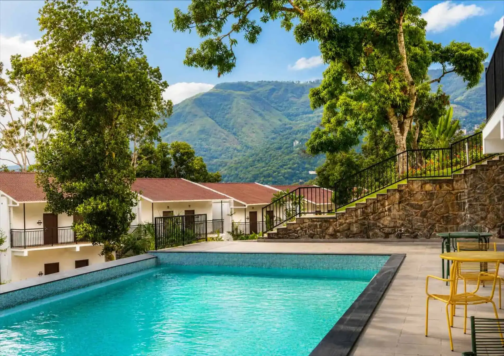 Turquoise pool with yellow bistro chairs and mountain backdrop
