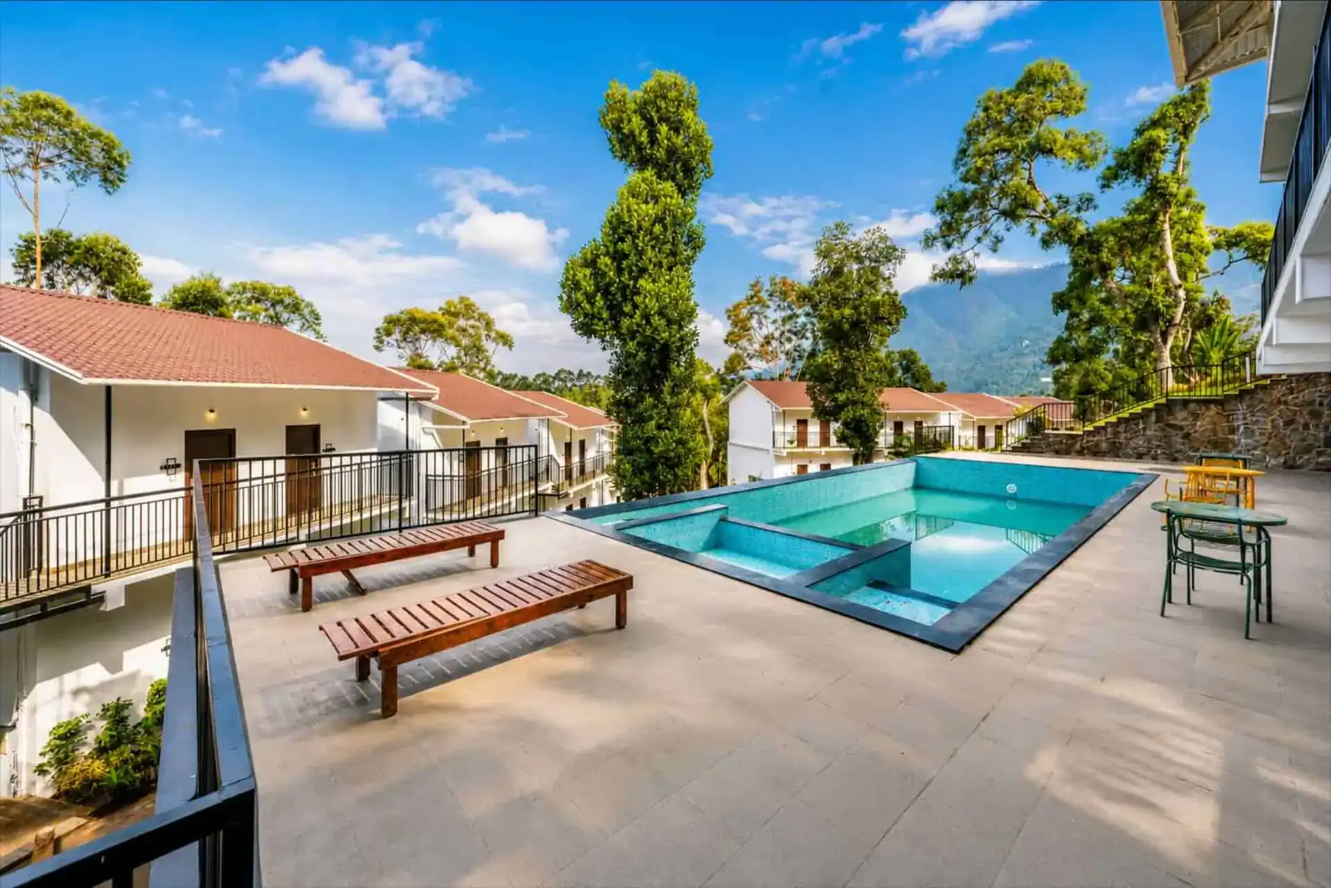 Luxury outdoor swimming pool deck with sun loungers at Vega Munnar