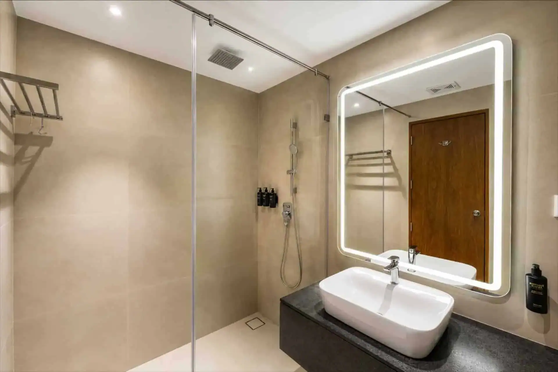 Walk-in shower and dark stone vanity with beige tile bathroom