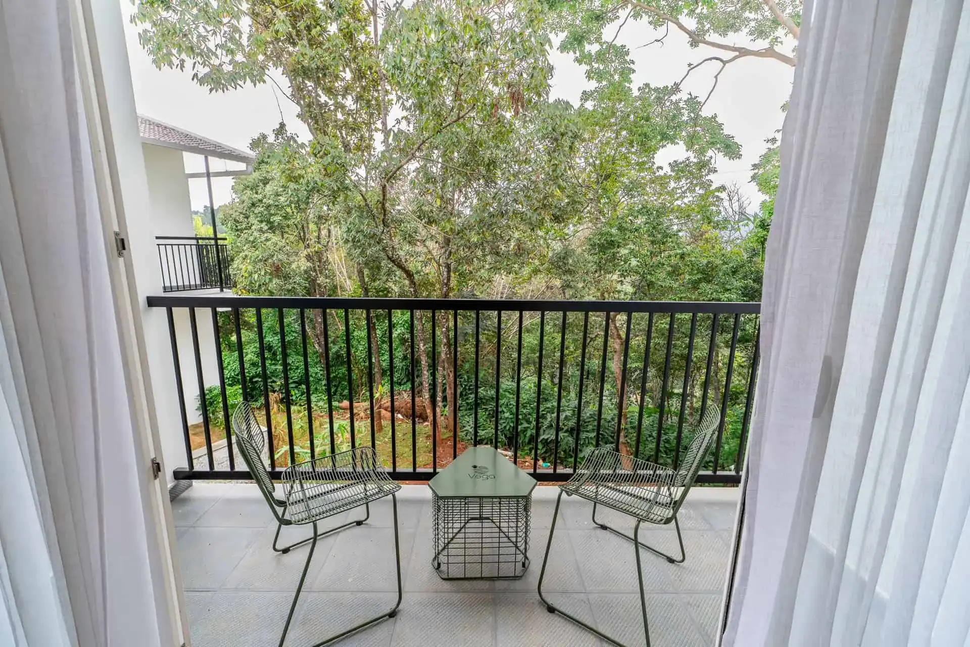 Vega Bliss Cottage private balcony with wire chairs and tropical tree view