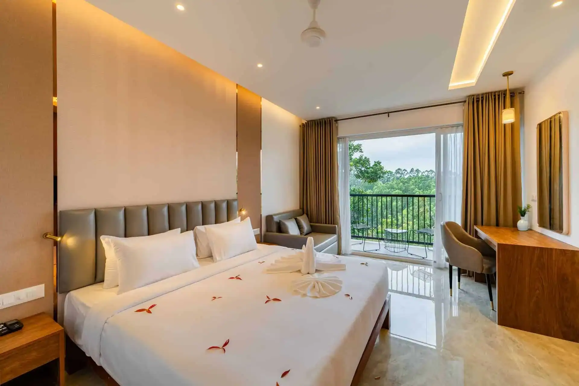 Vega Bliss Cottage interior with king bed, gold curtains and private balcony with lush green tree view at Vega Munnar